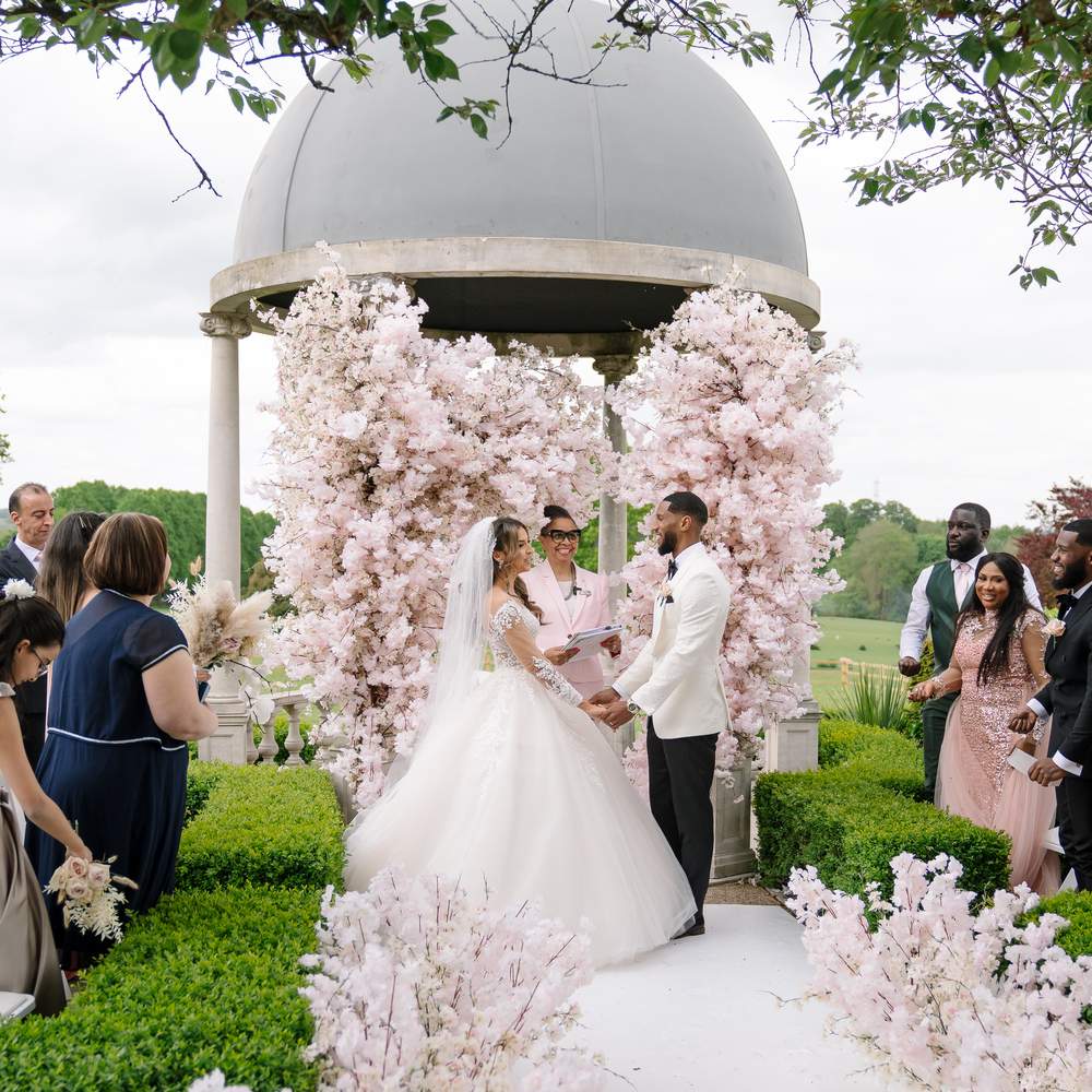 Amazing Nigerian outdoor civil Ceremony featuring pink blossom trees at Froyle Park's Dome.