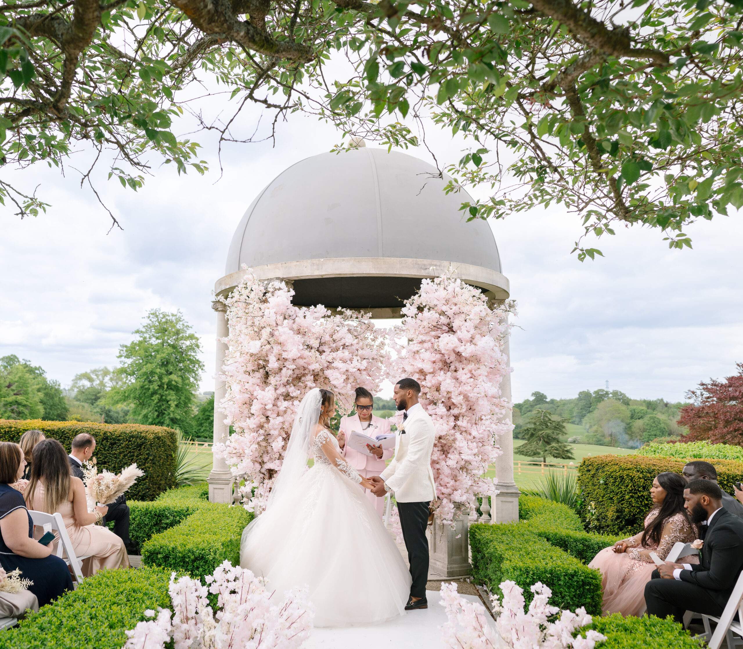 Amazing Nigerian outdoor civil Ceremony featuring pink blossom trees at Froyle Park's Dome.
