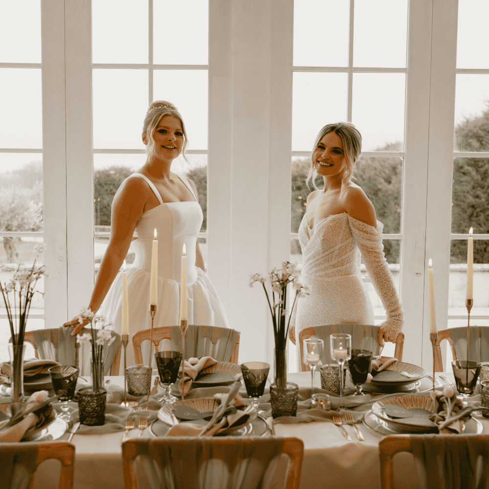 Two brides admire their reception decor in The Grand Ballroom at Froyle Park