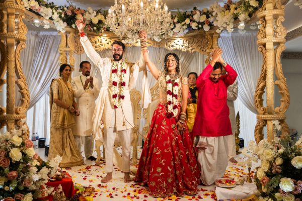 A Hindu Bride and groom celebrate cheer beneath their Manp in the Grand Ballroom at Froyle Park