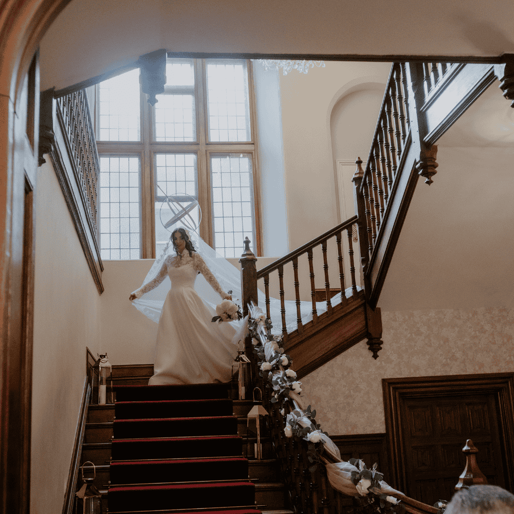 A Bride descends the elegant staircase into the Great Hall at Froyle Park