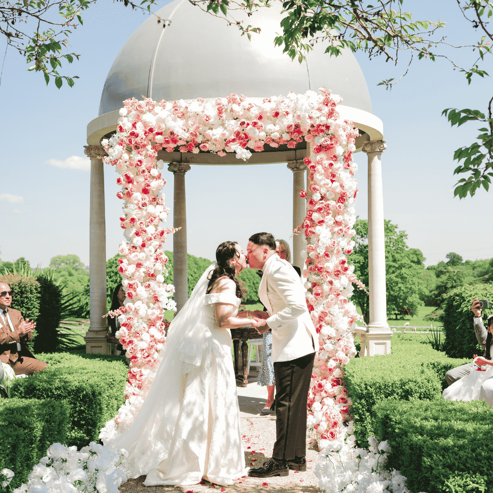 A Nepalese Bride & Groom dressed pose at the iconic outdoor wedding Dome at Froyle Park - a historic dry hire wedding venue just an hour from London which specialises in Asian weddings.