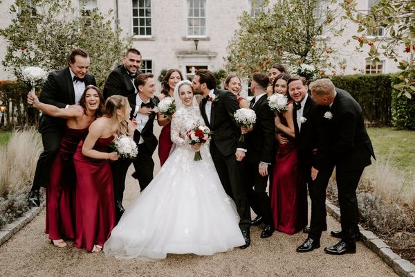 Bride and groom celebrating with their bridal party outside Froyle Park Surrey wedding venue.