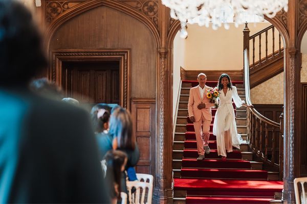 Bride and her Father descend stairs into the Great Hall at Froyle Park
