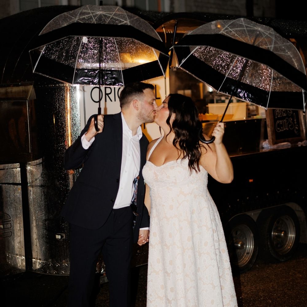 Bride and Groom beneath umbrellas in the courtyard at Froyle Park